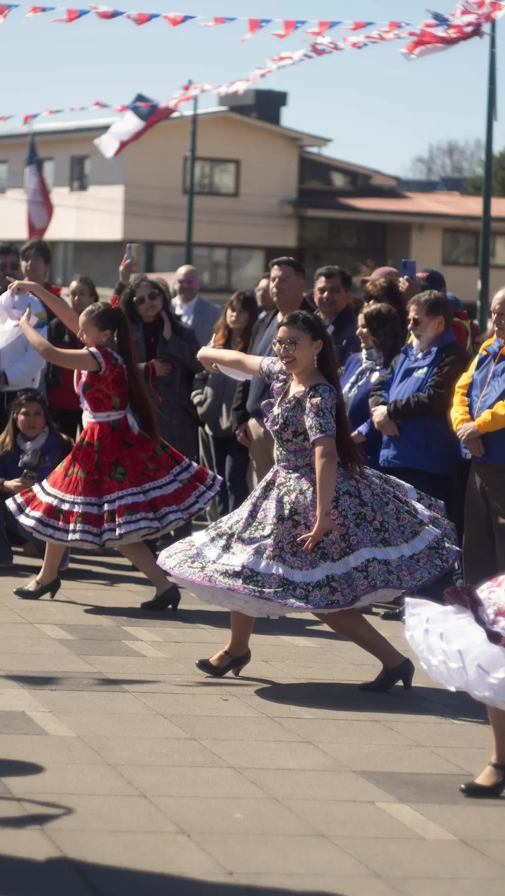 Bailarina con vestido floreado de china girando, la falda abierta por el movimiento, en una plaza.