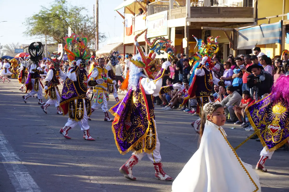 Multitud en la Fiesta de La Tirana con bailes religiosos y bandas de bronces en la calle.